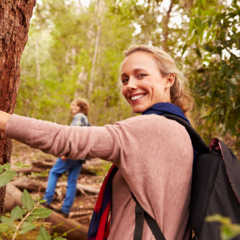 a middle aged woman with a beautiful smile walks in the forest