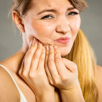 suffering blond woman holding her jaw