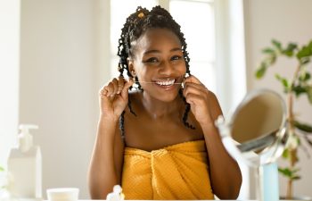 Perfect smile. Portrait of happy african american woman using dental floss at home, doing morning routine, sitting at vanity table, looking at camera and smiling